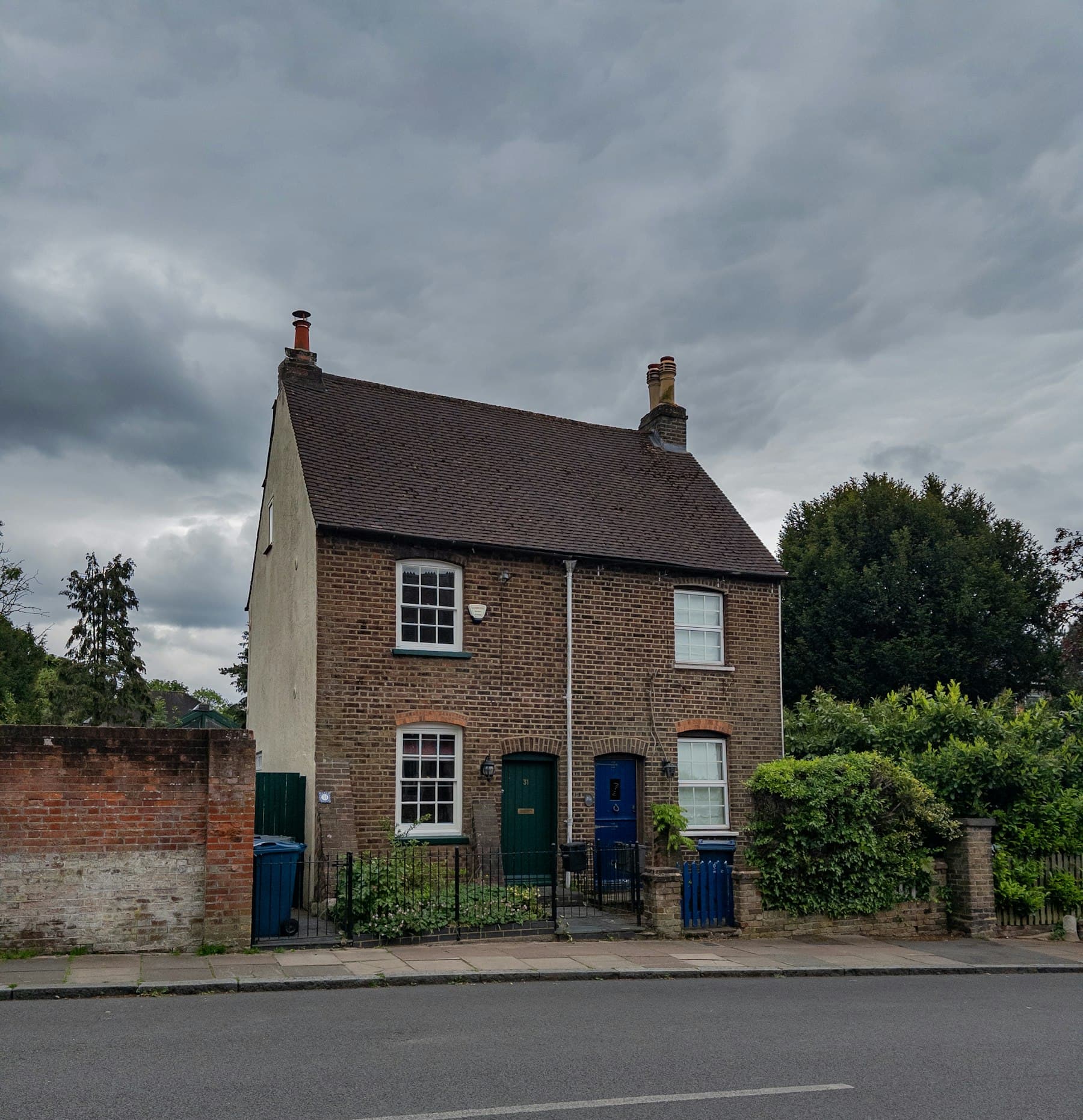 Pair of brick cottages with white sash windows and a tidy front garden