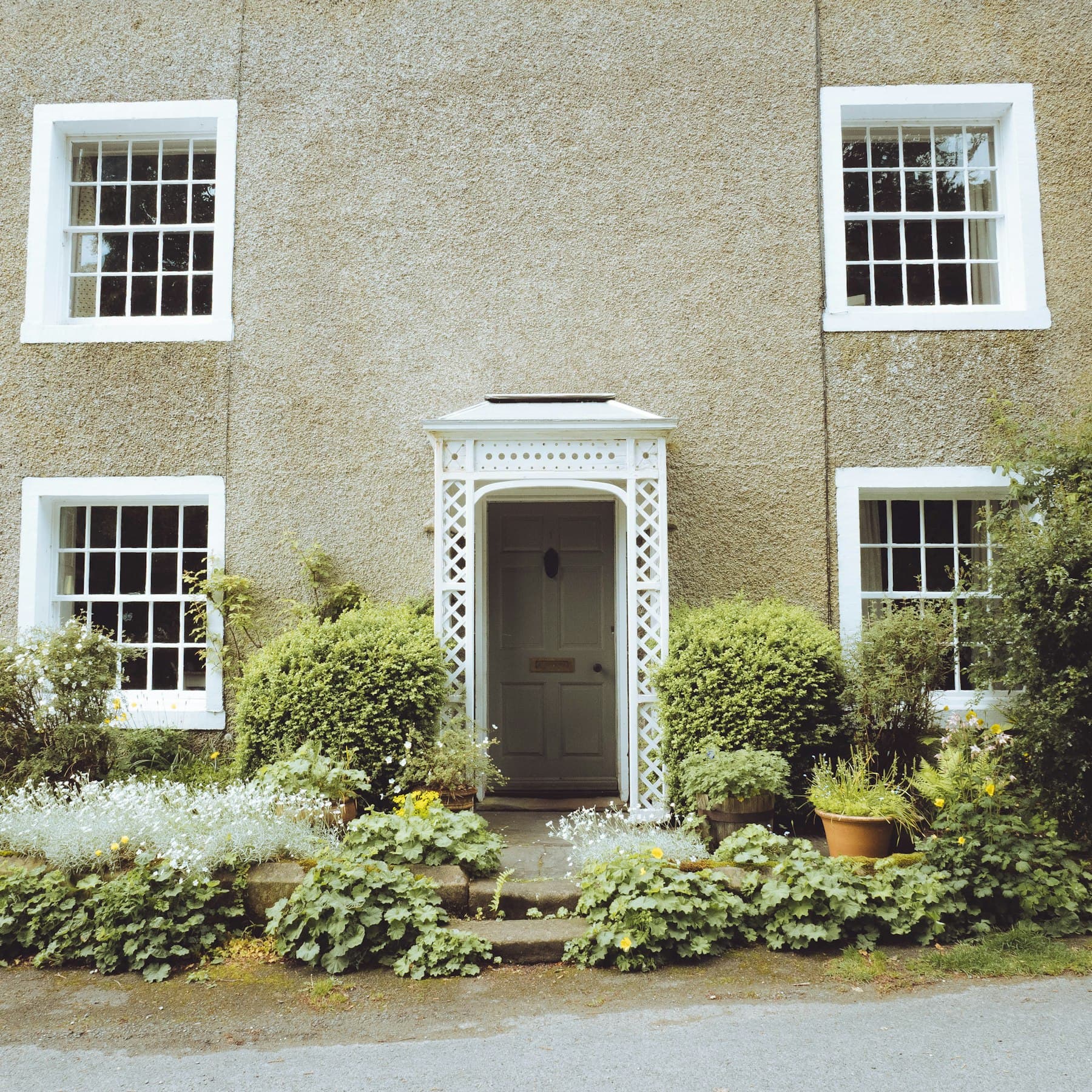 House with white sash windows, ornate porch and a well-kept front garden
